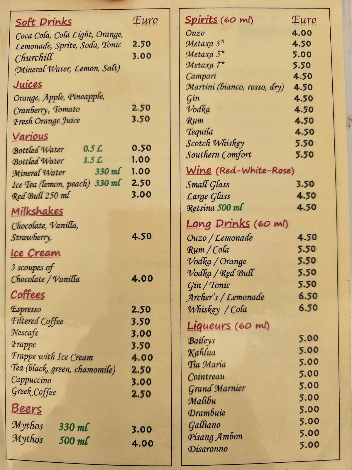 A cafe menu listing drinks, ice cream, cocktails, and shots with prices in Euros. Sections include soft drinks, juice, beer, wine, spirits, and coffee. Some items are highlighted in green or underlined.