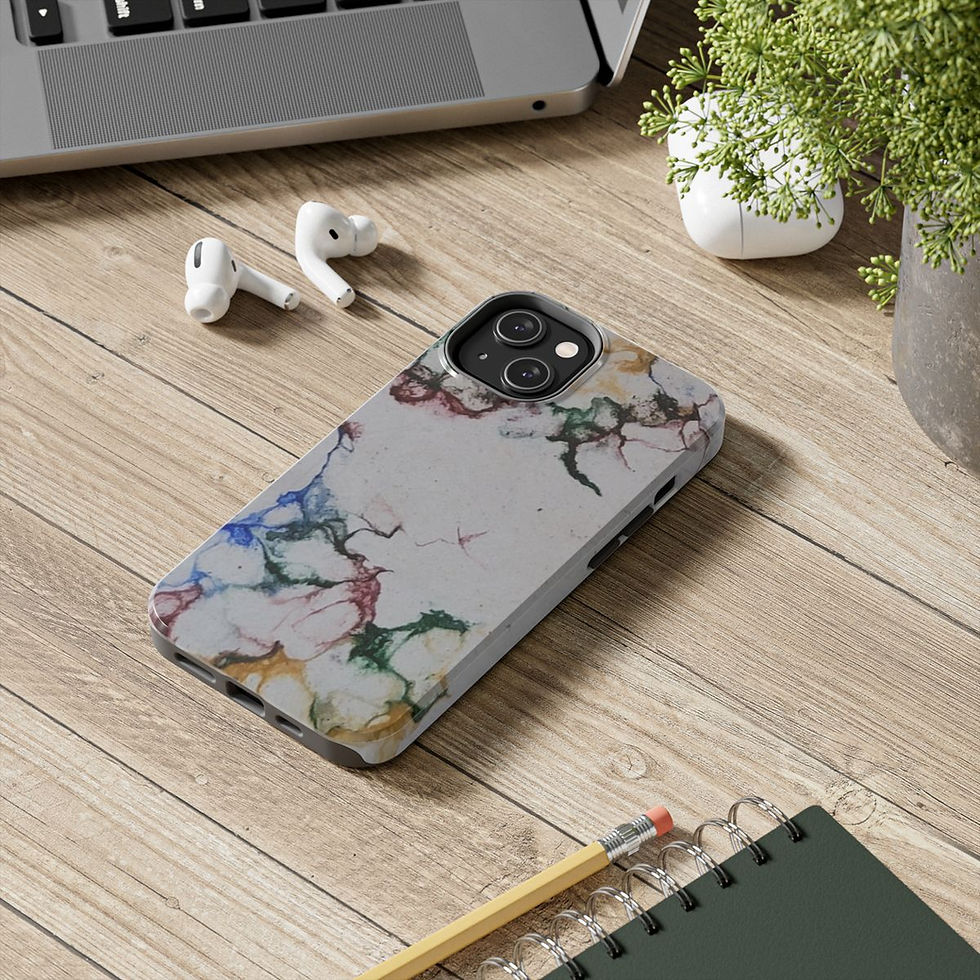 A smartphone with a colorful abstract case lies on a wooden desk near a laptop, wireless earbuds, a green plant, and a pencil