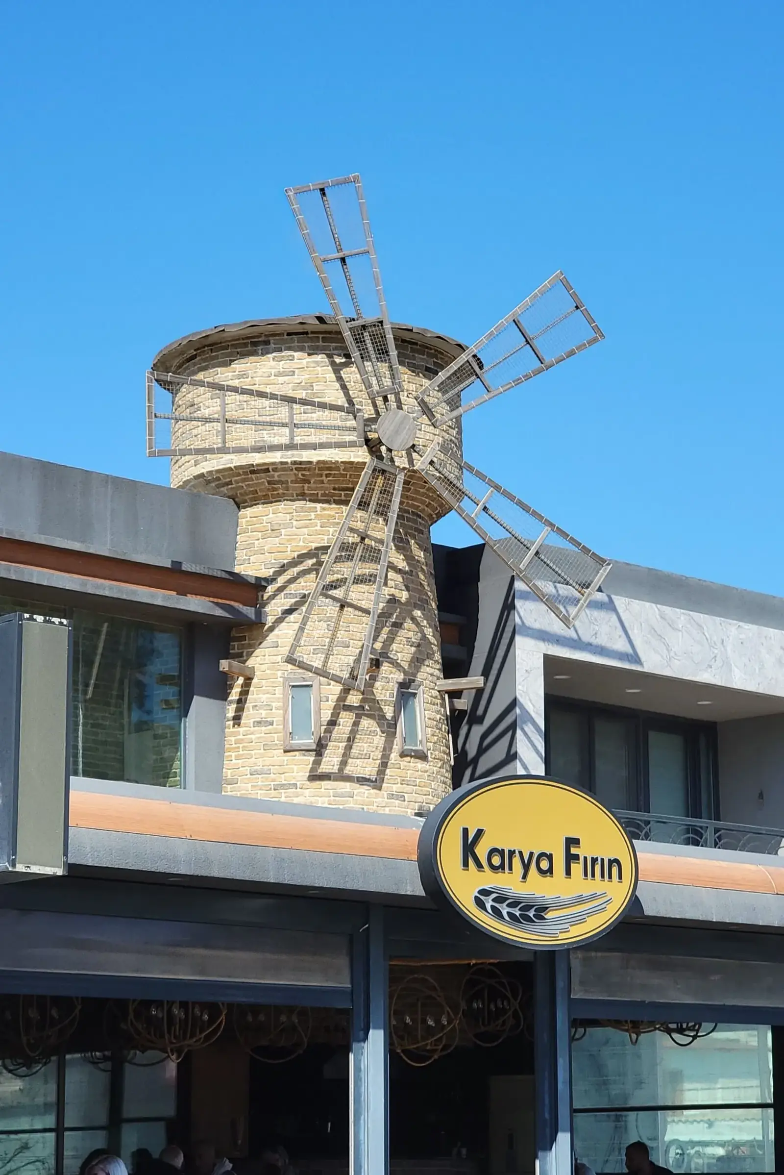 A modern building with a decorative windmill structure on the roof and a sign reading "Karya Finn" on the front.