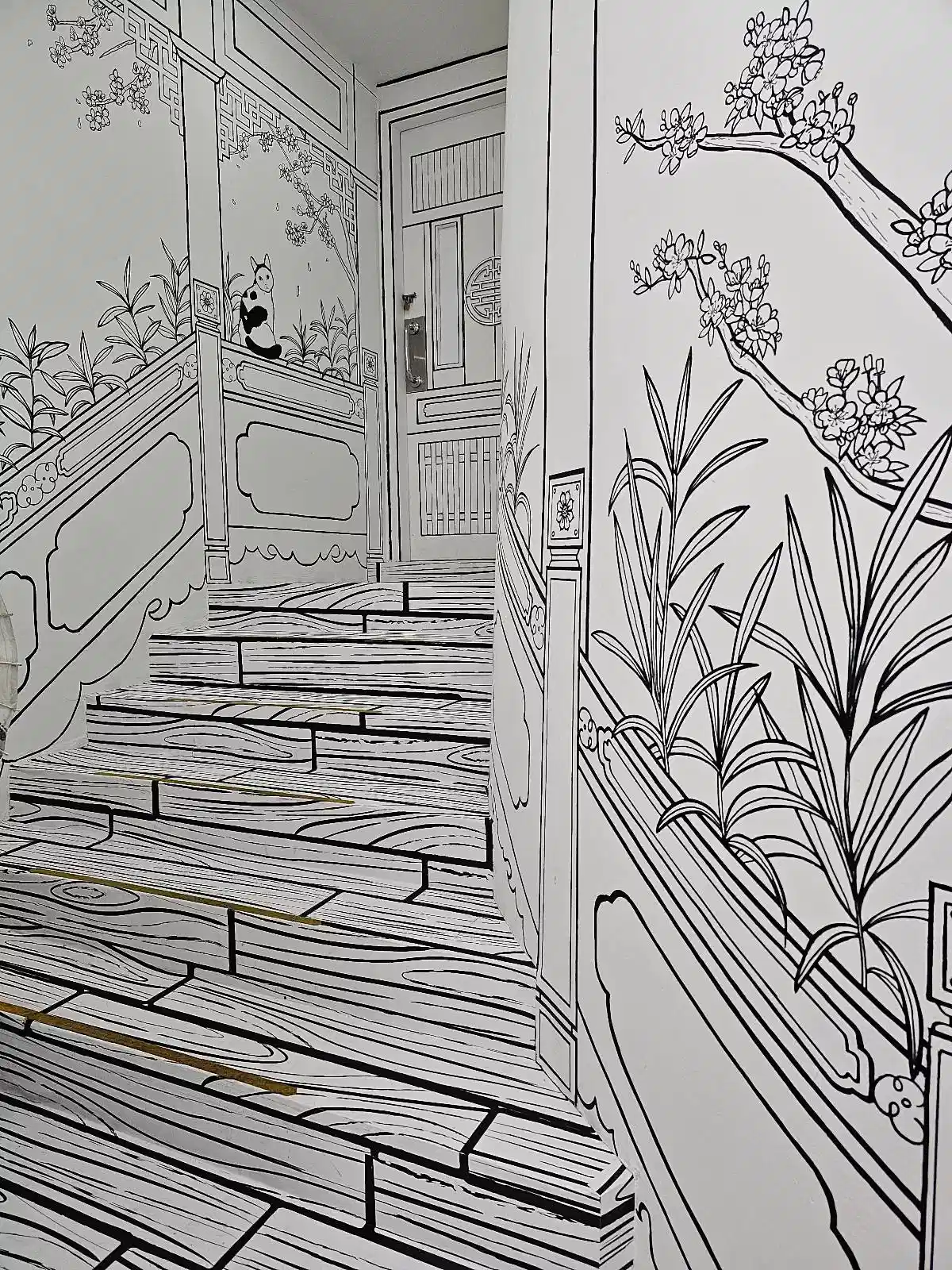 A staircase is designed to look like a black-and-white drawing, with sketch-like lines outlining the steps and railings. The walls feature illustrated plants and flowers, enhancing the artistic, two-dimensional effect of the scene.