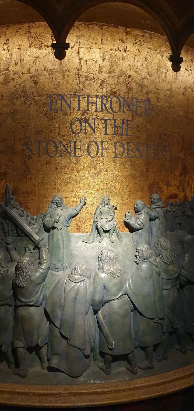 Stone relief depicting figures gathered beneath inscription about Robert the Bruce and the Declaration of Arbroath.