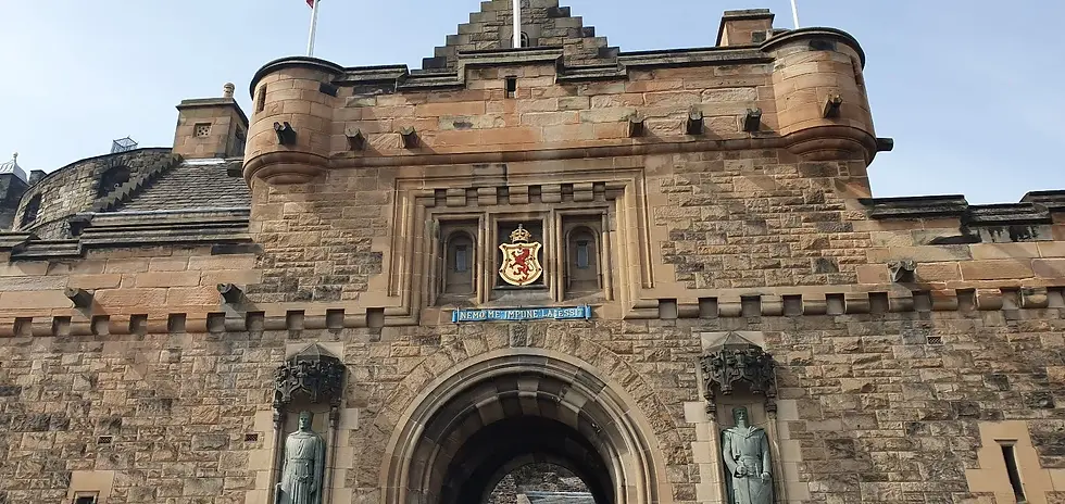 Stone castle entrance with two statues flanking an archway. A coat of arms and the text "Nemo Me Impune Lacessit" are above the arch.