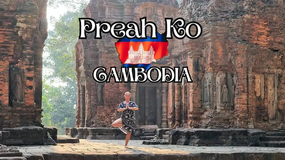 A person practices yoga at the ancient Preah Ko temple in Cambodia. The temple features intricate red-brown stonework.