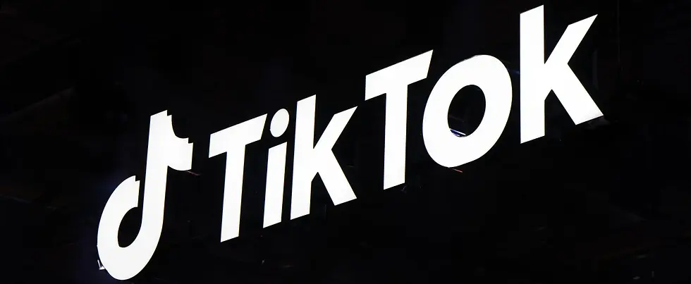 TikTok logo illuminated on dark background, social media platform icon representing short-form video content and creator culture.