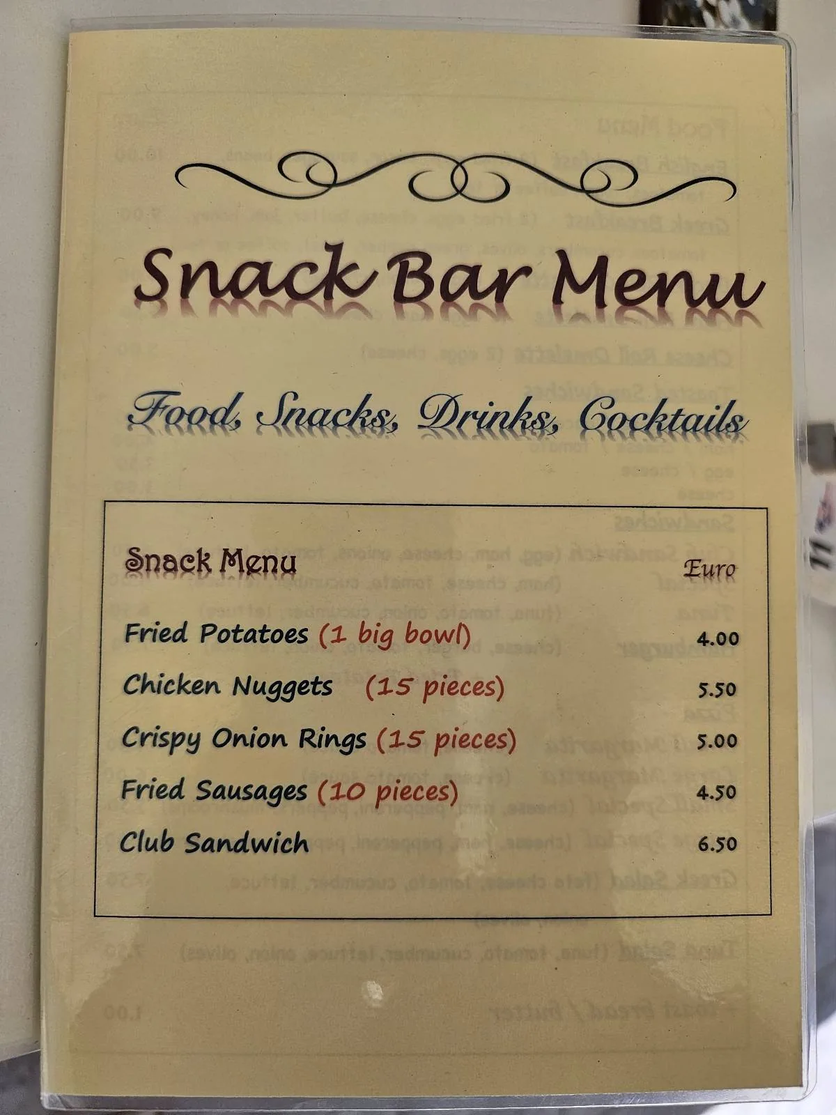 Snack bar menu showing food options and prices, including chicken nuggets, fish fingers, crispy onion rings, fries, and a club sandwich. Items are available in either half or full pound sizes.