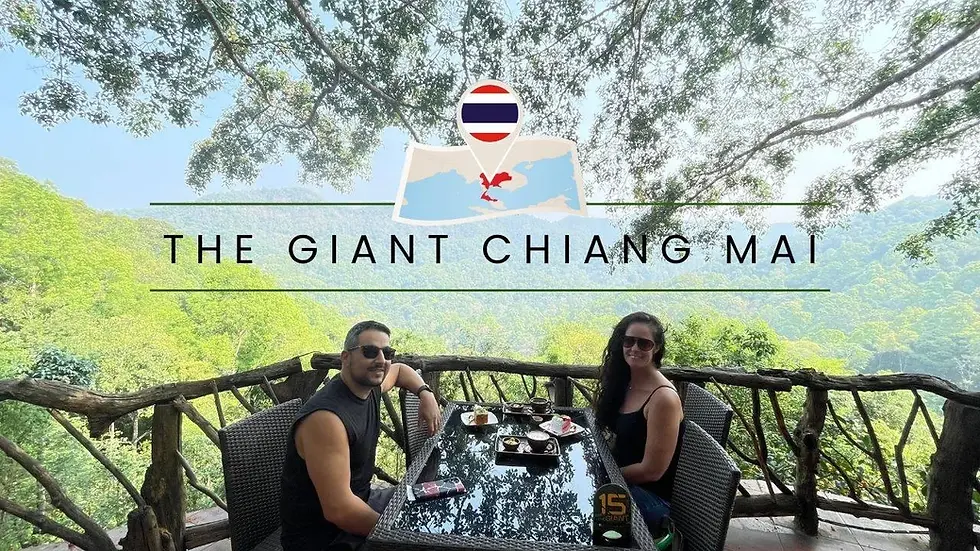 A couple dines at a wooden table with forest views. Text reads "The Giant Chiang Mai" over a backdrop of green foliage and blue sky.