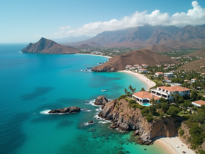 Aerial view of a coastal landscape in Los Cabos with turquoise water, sandy beaches, rocky cliffs, and luxury villas overlooking the sea. Mountains rise in the background under a partly cloudy sky.