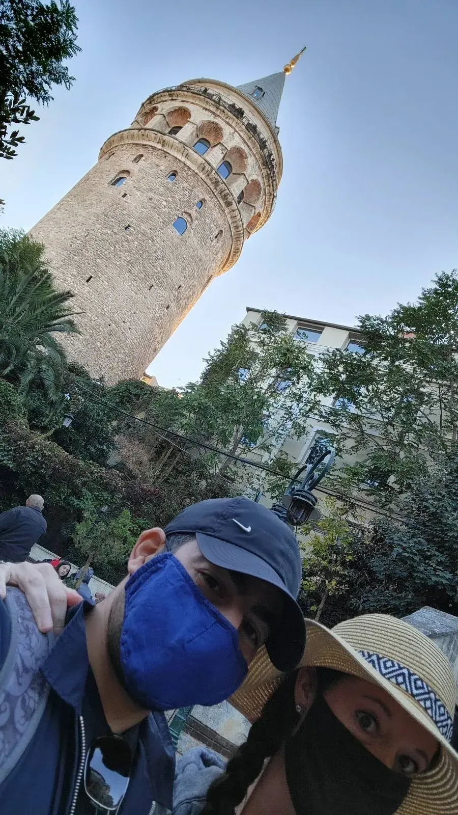 Two people wearing masks pose in front of the Galata Tower.