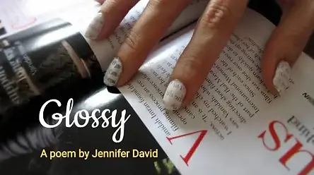 A close-up of a hand with white patterned nail art resting on an open glossy magazine. The text reads "Glossy: A poem by Jennifer David" in white and yellow fonts.