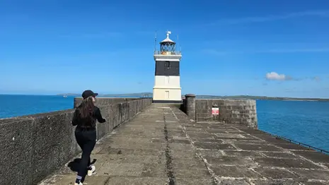 Black and white lighthouse at the end of Holyhead Breakwater with sea and blue sky on Anglesey, Wales.