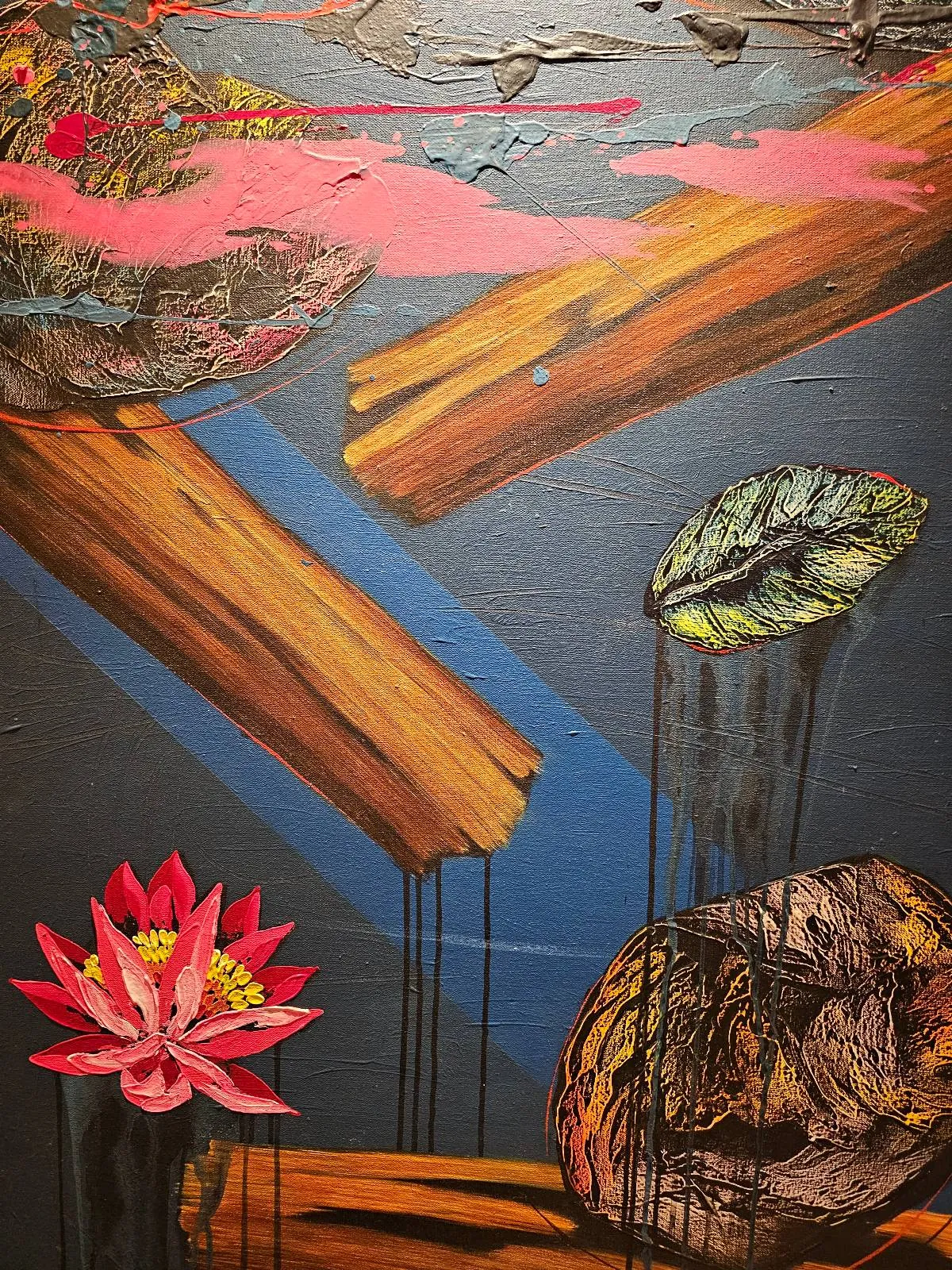 Abstract painting featuring floating wooden planks, a bright pink water lily, two green lily pads, and blue diagonal shapes, all set against a dark textured background with dripped paint accents.