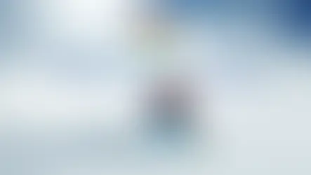 Skier in red and blue gear on snowy slope with blue sky. Text: "SKIING IN GULMARG" and Indian flag. Energetic and scenic.