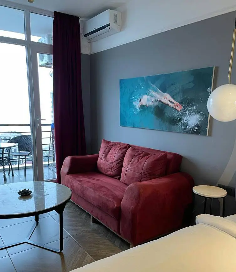 A living room with a sofa and wall canvas, next to patio doors leading to a balcony.