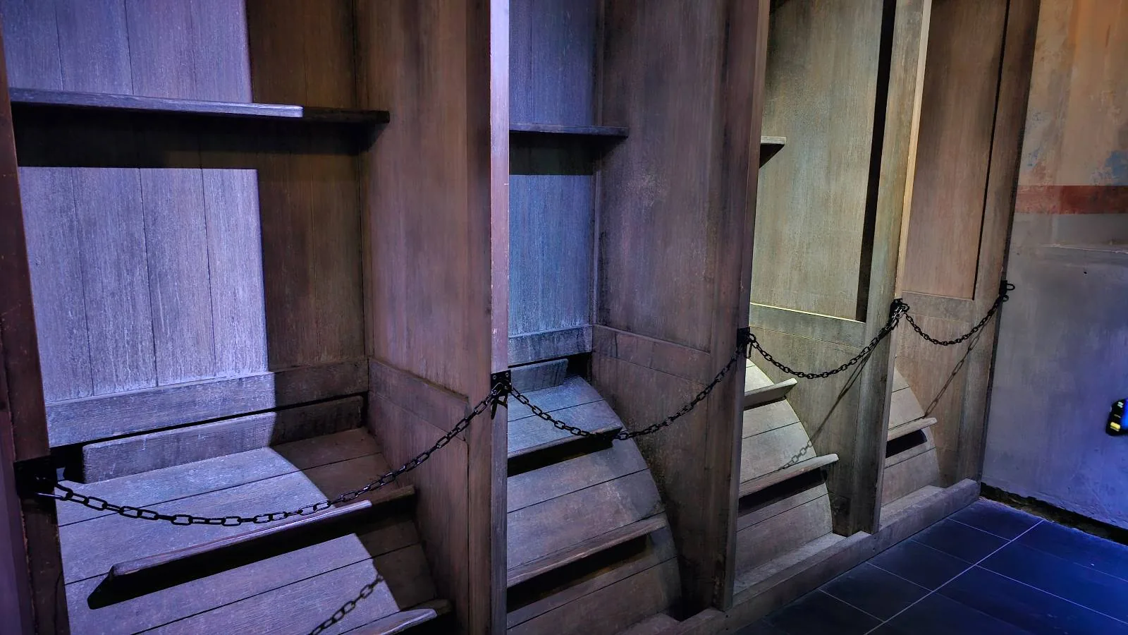 Wooden treadmill with black metal railings, illuminated by soft light in an indoor setting, roped off for restricted access.