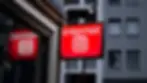 Red sign with "Internet" and "@" symbol, mounted on a building. Urban background with gray windows; streetlights illuminating the scene.