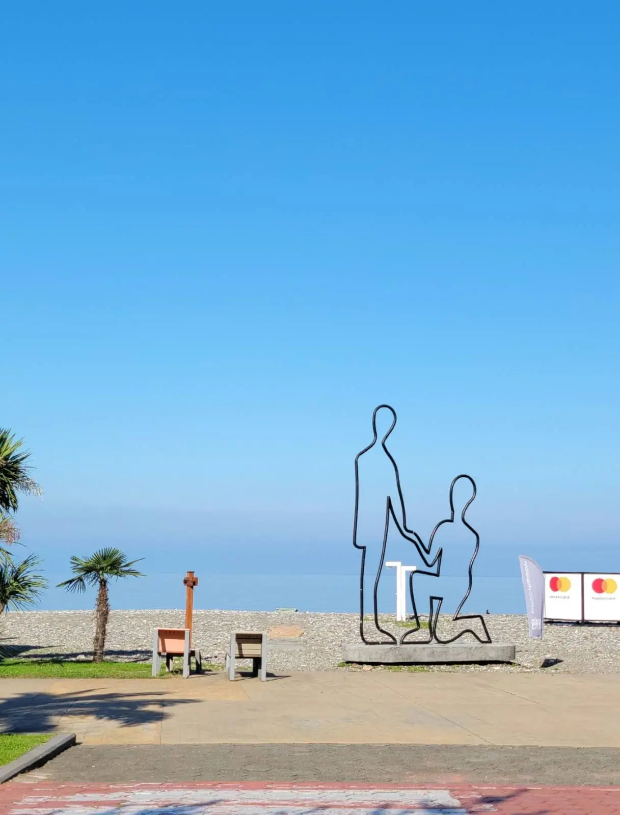 Hollow wire outline monument of man kneeling and holding the hand of a woman, against the backdrop of the Black Sea.