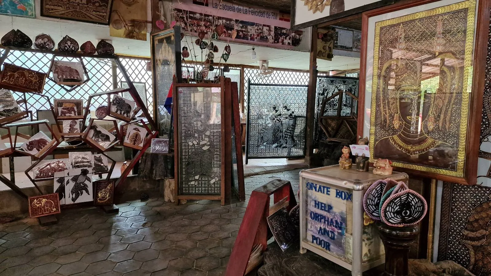 A room filled with vintage memorabilia, including framed photographs, paintings, and display cases. The walls are adorned with various historical items, such as an ornate frame and patterned textile. The floor is tiled, adding to the nostalgic ambiance.