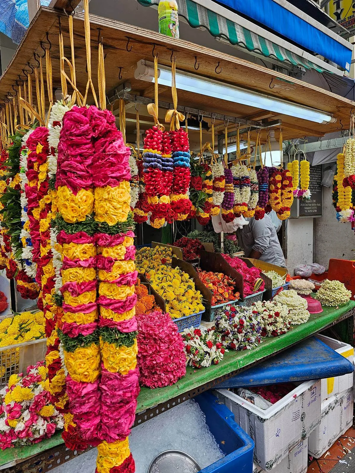 Brightly colored flower garlands hanging from a market stall in Little India, Singapore.