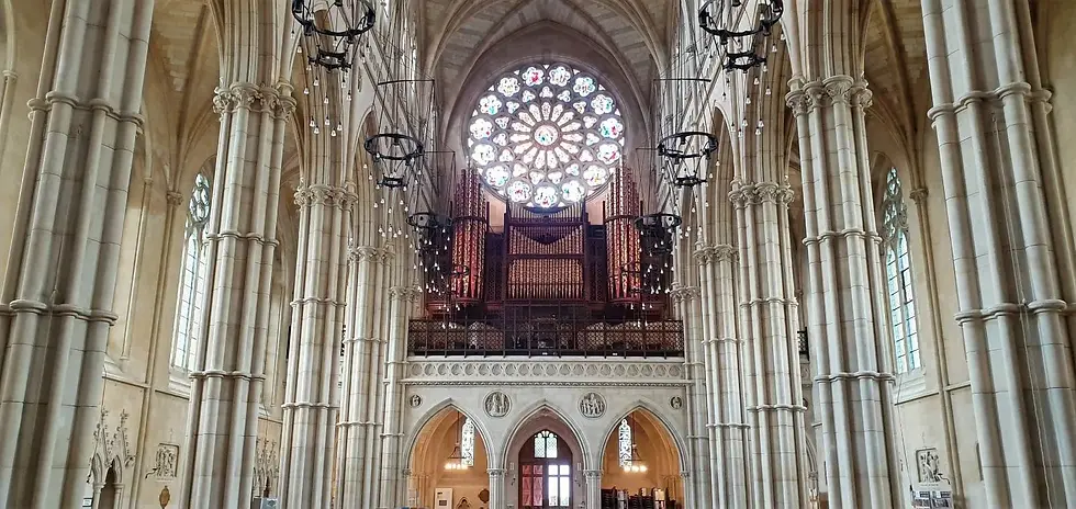 Inside a grand cathedral with tall columns and a large stained glass rose window. Ornate chandeliers and pipe organ visible. Majestic ambiance.
