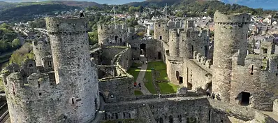 Aerial view of Conwy Castle with stone towers and town below, Wales.
