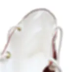 A close-up of a white bag with gold eyelets and white rope handles, featuring a red trim along the edge.