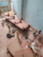 Dilapidated classroom with broken chairs and debris on the floor.