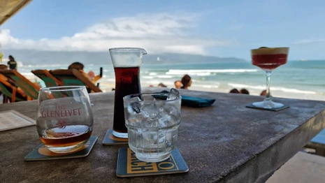 Cocktails and drinks on a table at Esco Beach Bar in Da Nang, with the beach and ocean in the background.