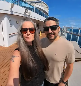 Jenn and Leon standing together on the deck of a Princess cruise ship under a clear blue sky, smiling during their cruise from Florida.