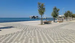 Beachfront promenade in Durrës, Albania with palm trees, modern paving, and a clear blue sky overlooking the Adriatic Sea.