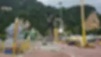 Signage points to landmarks. Colorful steps lead to Batu Caves amid lush hills. A golden statue stands prominently. Cars and tents nearby.