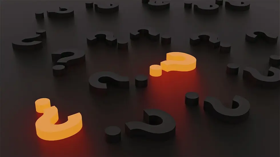 Several black question marks lie on a dark surface, while two glowing orange question marks stand out in the foreground.