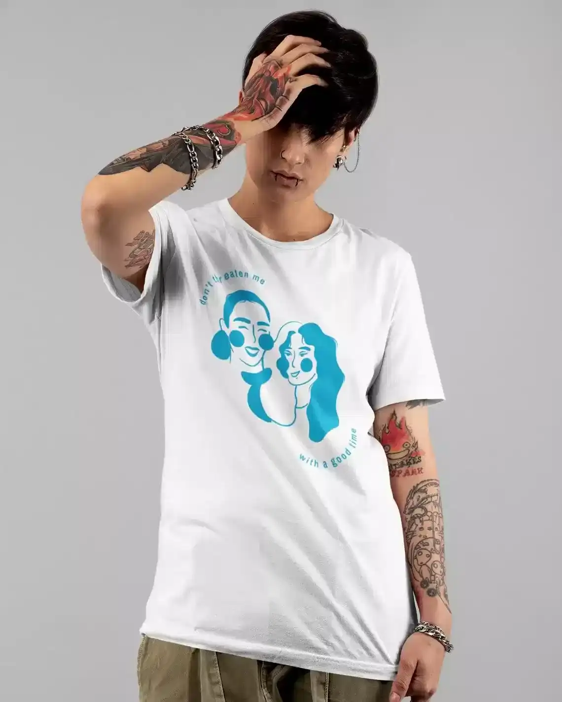 A person with tattoos on their arms is wearing a white T-shirt featuring a blue graphic of two faces.