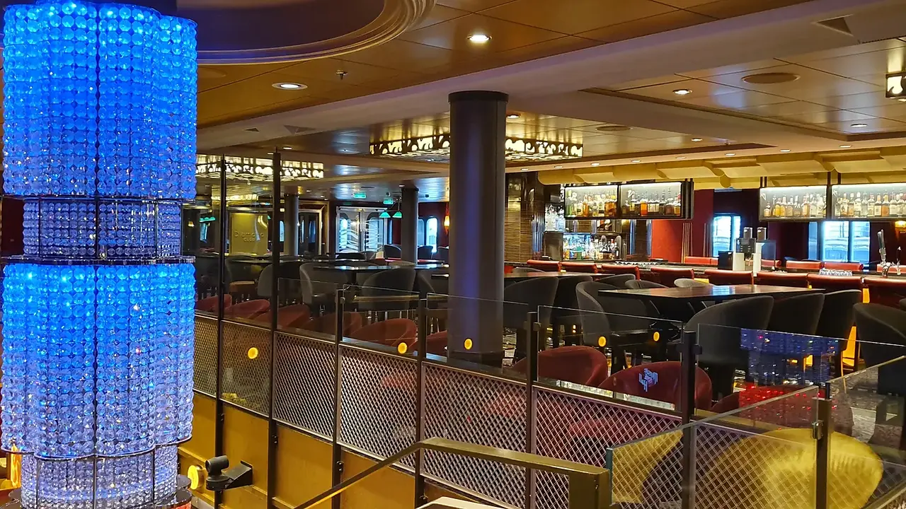 The multi-level Royal Esplanade inside Ovation of the Seas with a glowing blue light installation.