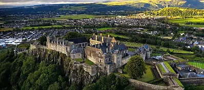 Aerial view of Stirling Castle perched on a rocky hill, overlooking the town and surrounding countryside in central Scotland.