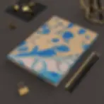 Blue and beige peacock feather journal from the Mexican Tile Style collection on desk.