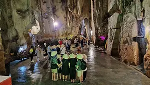 A group of tourists wearing traditional Vietnamese conical hats standing inside a massive, naturally lit limestone cavern at Marble Mountain in Da Nang.