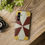 Thumbnail: A smartphone with a geometric, red, yellow, and white patterned case lies on a wooden surface next to a vintage camera.