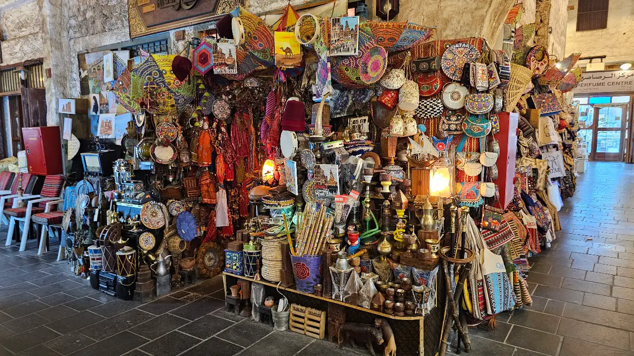 A vibrant alleyway lined with traditional market stalls and lanterns at Souq Waqif in Doha, Qatar, during an evening tour.