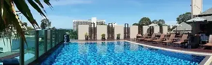 A beautiful outdoor swimming pool and sun loungers at the April Suites hotel in Pattaya, Thailand.