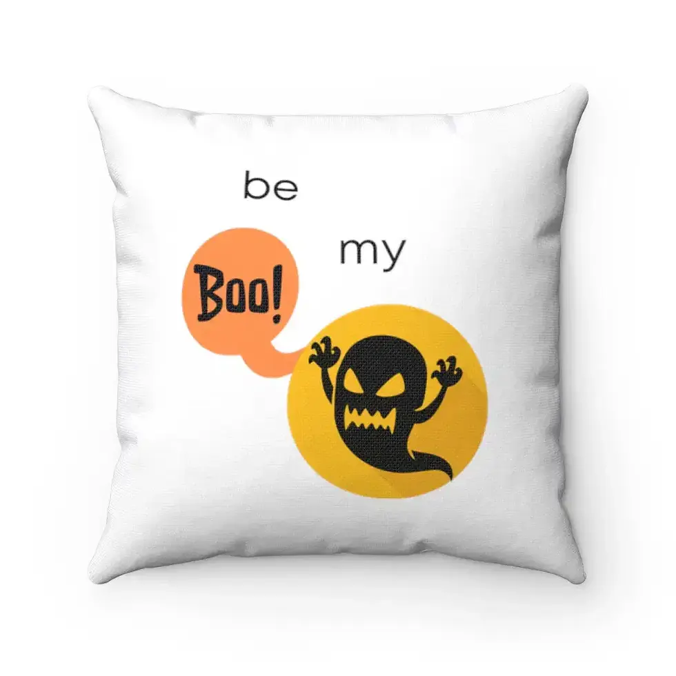 A white cushion features a playful design with a cartoon ghost inside an orange circle, raising its arms.