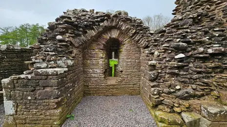 Arched stone ruin inside White Castle with layered masonry and gravel floor in Monmouthshire, Wales.