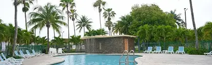 Sunny outdoor swimming pool and palm trees at Fairway Inn Florida City near the Florida Keys.