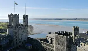 Caernarfon Castle overlooking the Menai Strait, with medieval stone towers and coastal views in North Wales.