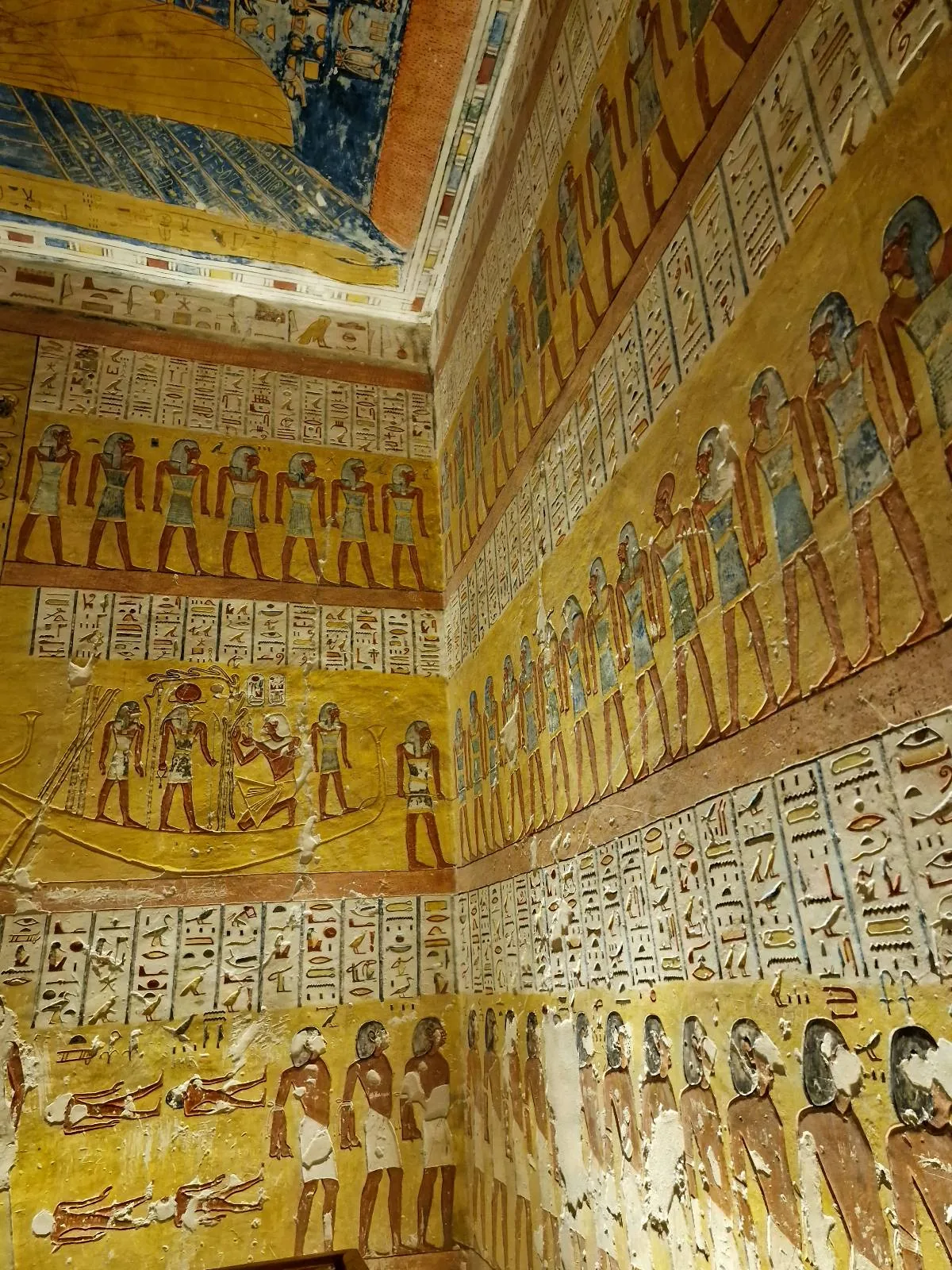 Interior view of an ancient Egyptian tomb with detailed wall paintings depicting figures and hieroglyphs in vibrant colors.