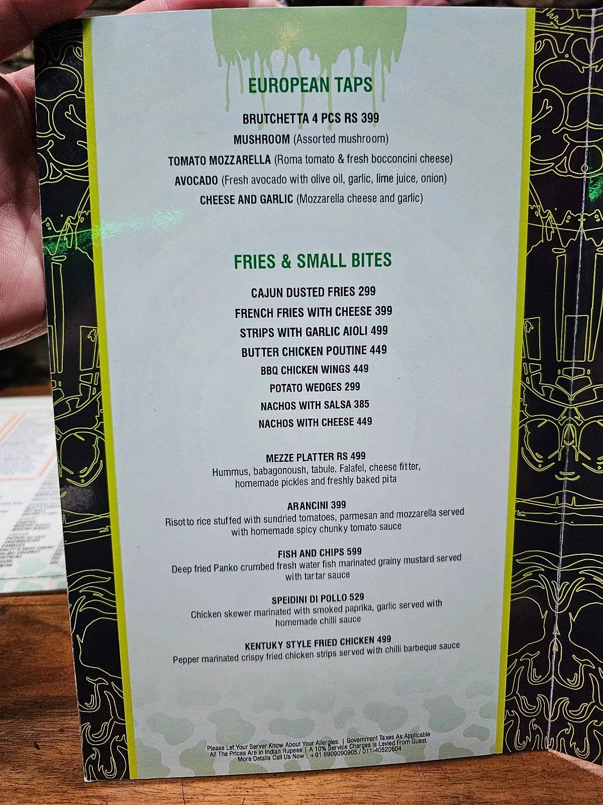 A restaurant menu featuring "October Tips," listing drinks and small bites. The menu has a green border and decorative black background, with items like fried gator bites, pickle chips, and themed cocktails.