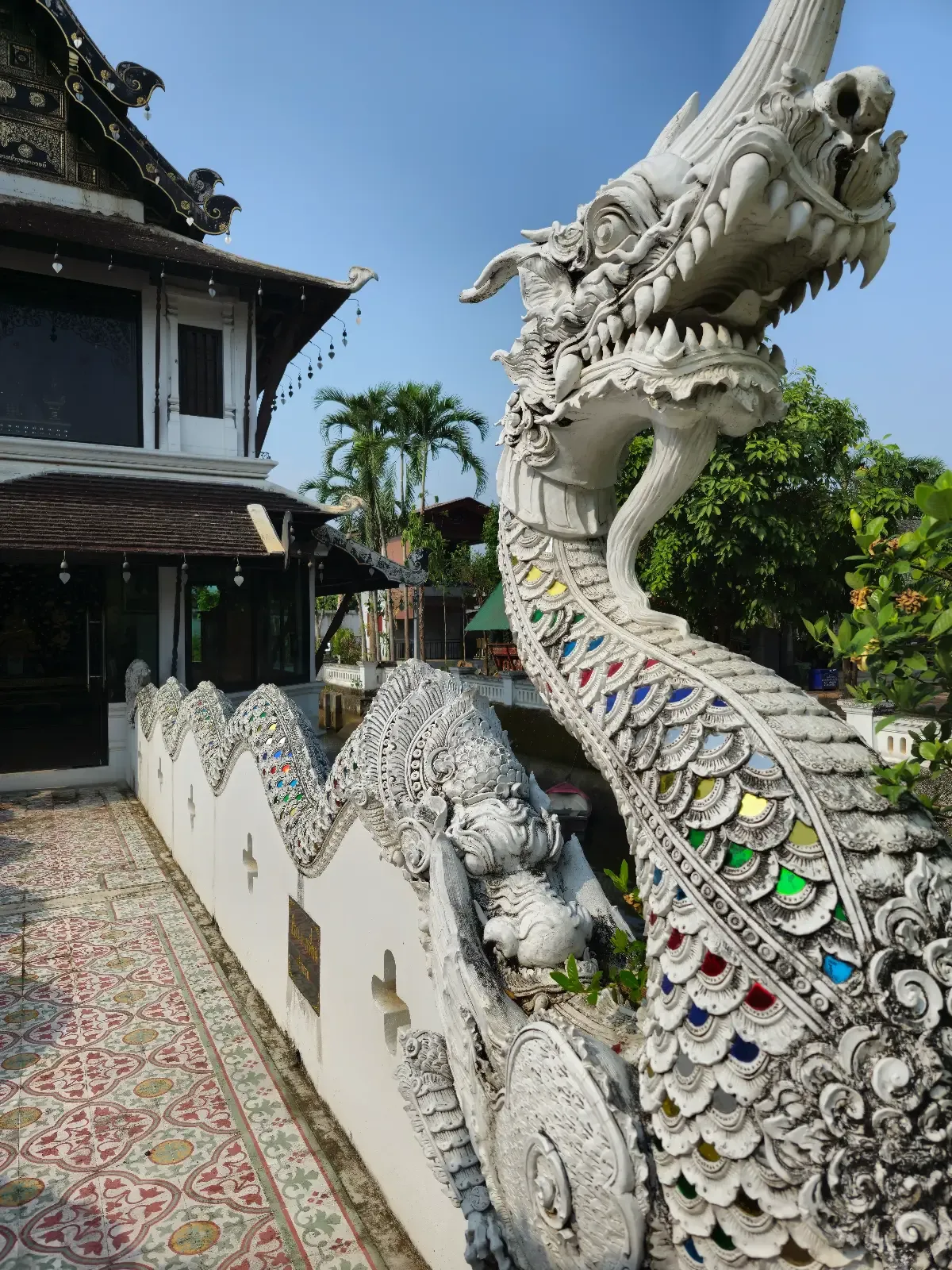 Detailed white naga balustrade with colourful mosaic inlays at Wat Sri Mung Muang.
