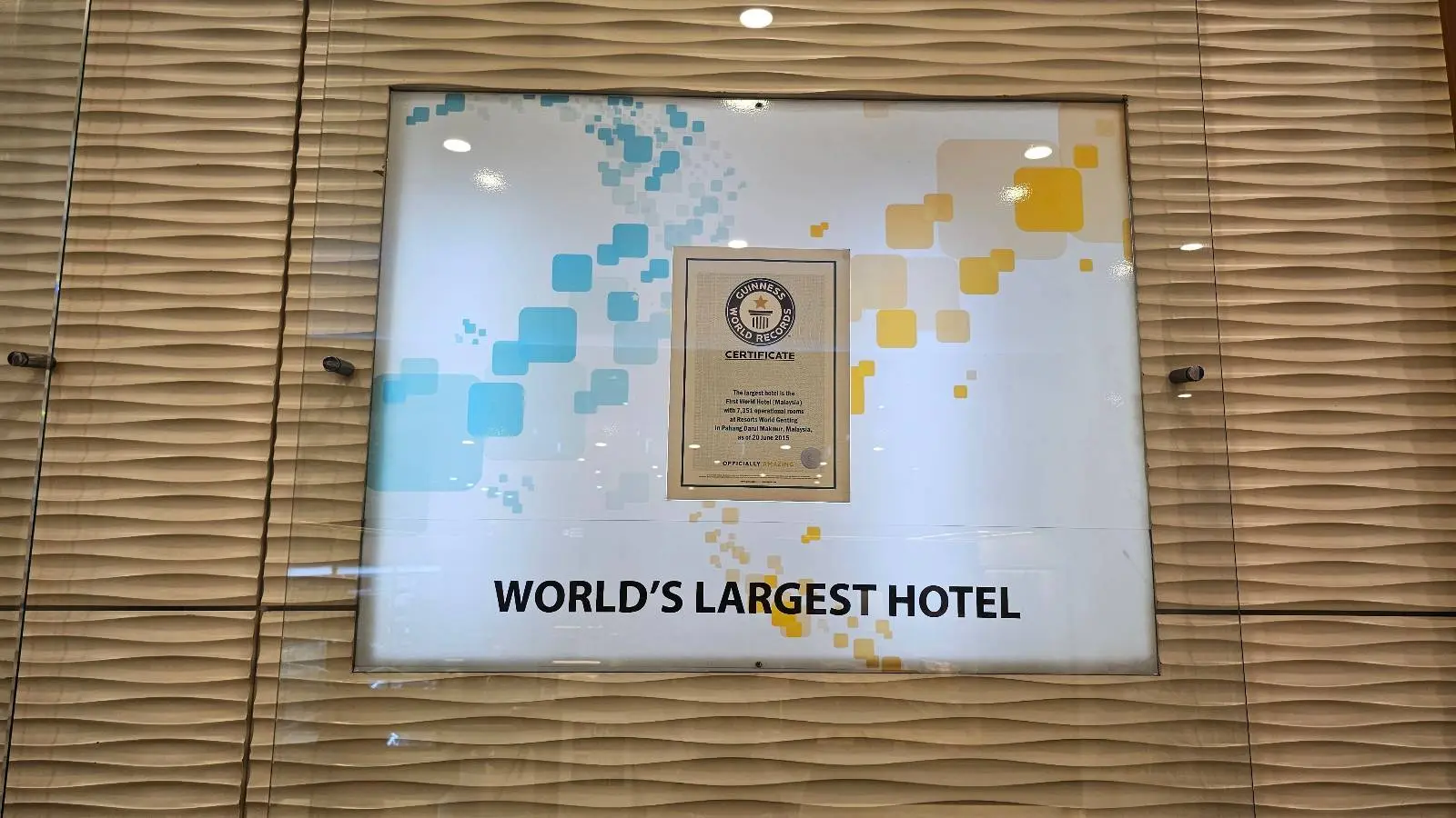 A plaque displayed on a patterned wall reads "WORLD'S LARGEST HOTEL" beneath the emblem of the Guinness World Records and some colorful geometric designs.