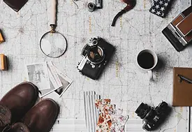 Flat lay of essential travel items including camera, map, passport, and accessories representing travel planning and adventure.