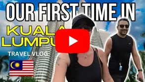 Jenn and Leon in front of the Petronas Twin Towers during their digital nomad travel vlog in Kuala Lumpur, Malaysia.