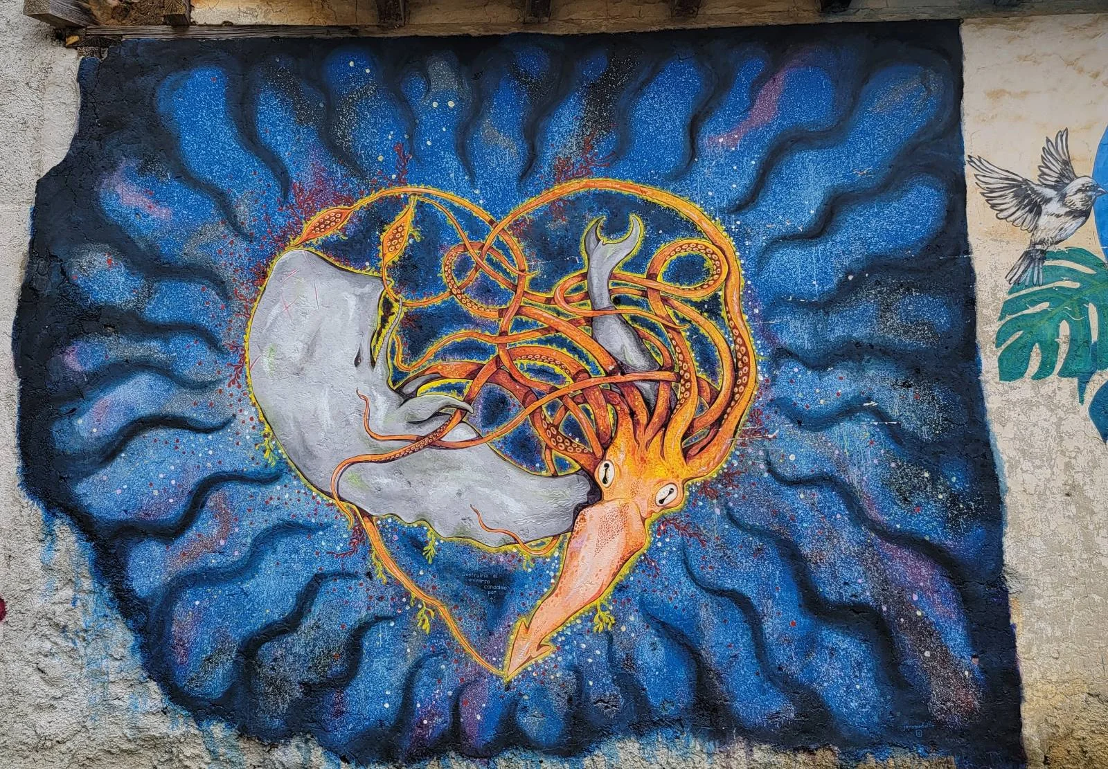 A colorful illustration featuring a whale and a squid intertwined in the shape of a heart against a vibrant blue background with swirling patterns. The squid's tentacles wrap around the whale, creating a harmonious and whimsical scene.